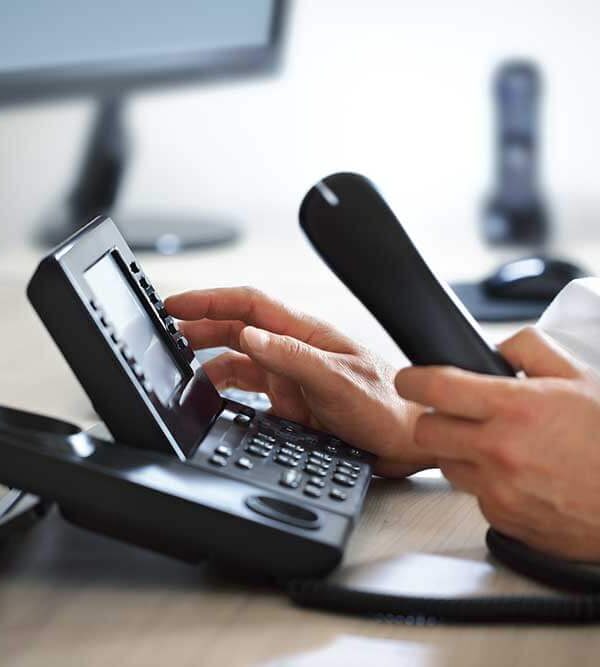 A man is using a VoIP telephone at a desk.