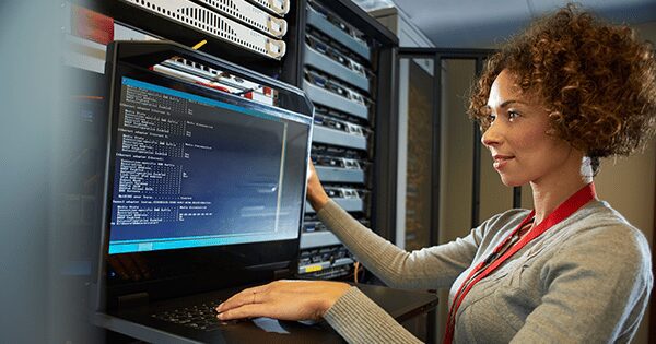 A woman working on a computer in a server room.