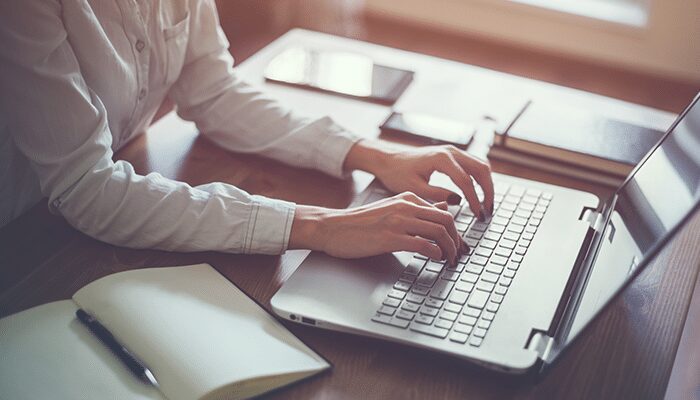 A woman typing on a laptop at a desk.