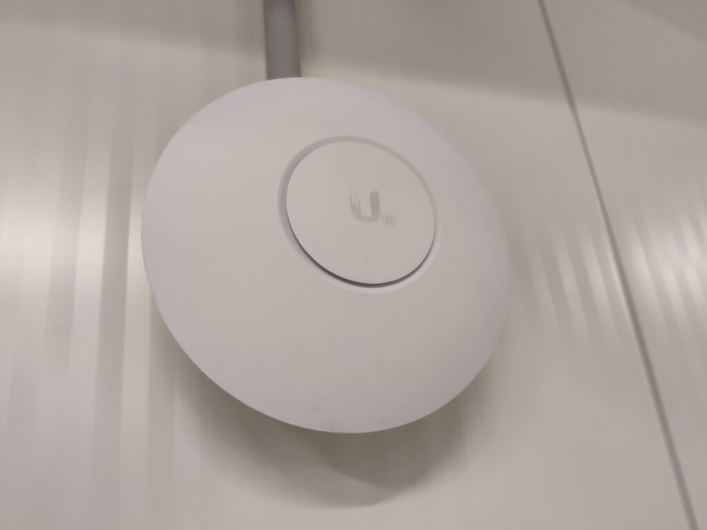 A ubiquiti wireless access point mounted on a wall.