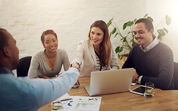 A group of people shaking hands at a meeting table.