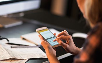 A woman using a cell phone at a desk.