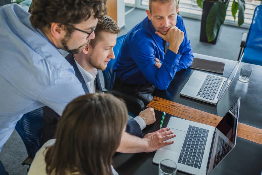 Four business people in Worcester sitting around a table looking at a laptop while receiving Managed IT Services.