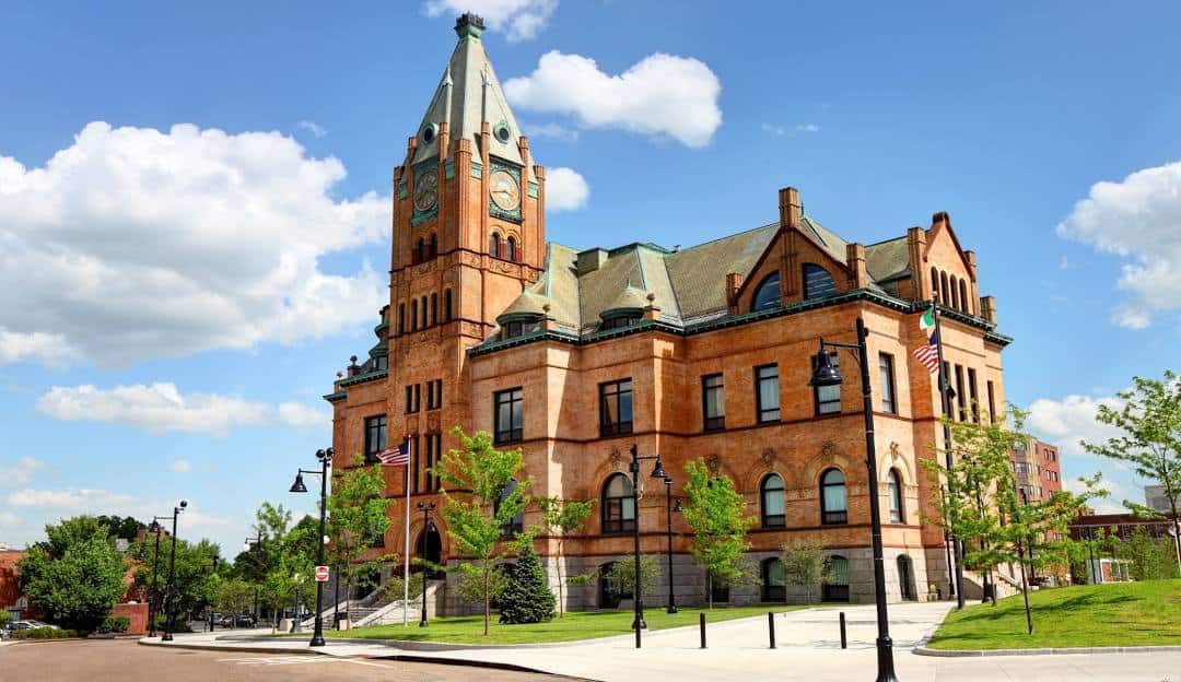 Historic brick building with a clock tower under a blue sky with fluffy clouds, now housing managed IT services in Brockton.