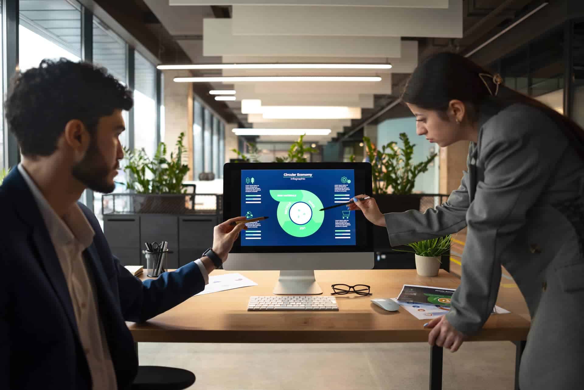 Two professionals discussing a digital business strategy on a computer screen in a modern office setting to get the most out of technology.