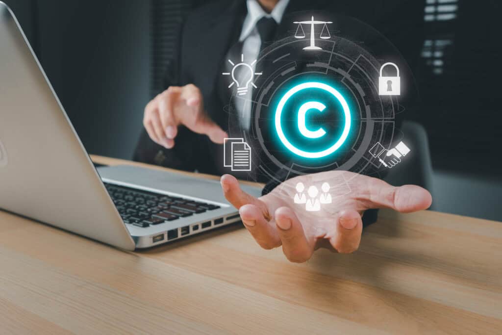 A person in formal attire works on a laptop, projecting floating digital icons including a copyright symbol, lightbulb, scales, lock, document, and people network above their hand. The imagery highlights the significance of CTDPA and CIS Compliance in today's digital landscape.