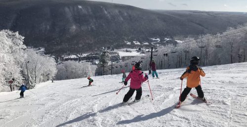 Skiers descending a snow-covered slope with a mountain landscape in the background, reminiscent of a managed IT services adventure in Bristol.