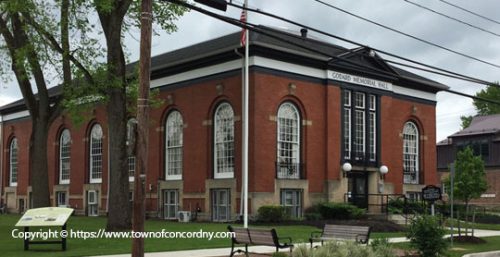 A red-brick building with large arched windows and an American flag on the lawn, identified as Concord Memorial Hall. The scene includes trees, a bench, and a sign with historical information about how managed IT services helped preserve its legacy. A red-brick building with large arched windows and an American flag on the lawn, identified as Concord Memorial Hall. The scene includes trees, a bench, and a sign with historical information about how managed IT services helped preserve its legacy.