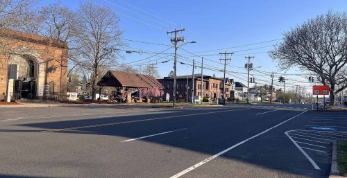 A clear day at a quiet intersection in a small town, managed IT services Portland prominently displayed on one of the commercial buildings, with a mix of traffic signals.