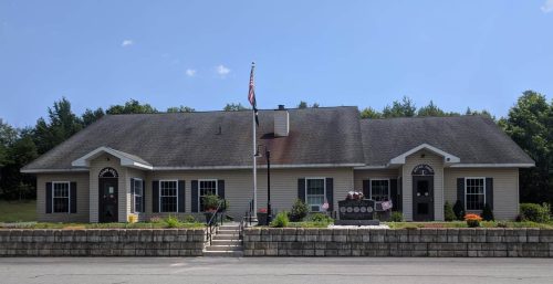 Single-story building with a central entrance flanked by symmetrical windows, managed IT services in Providence, an American flag out front, and a clear blue sky in the background.