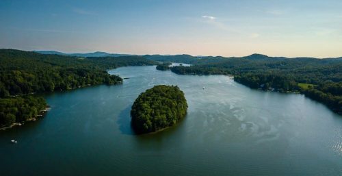 Aerial view of a serene lake with forested islands and surrounding greenery, resembling the tranquility one might find away from the bustling world of managed IT services in Salem.